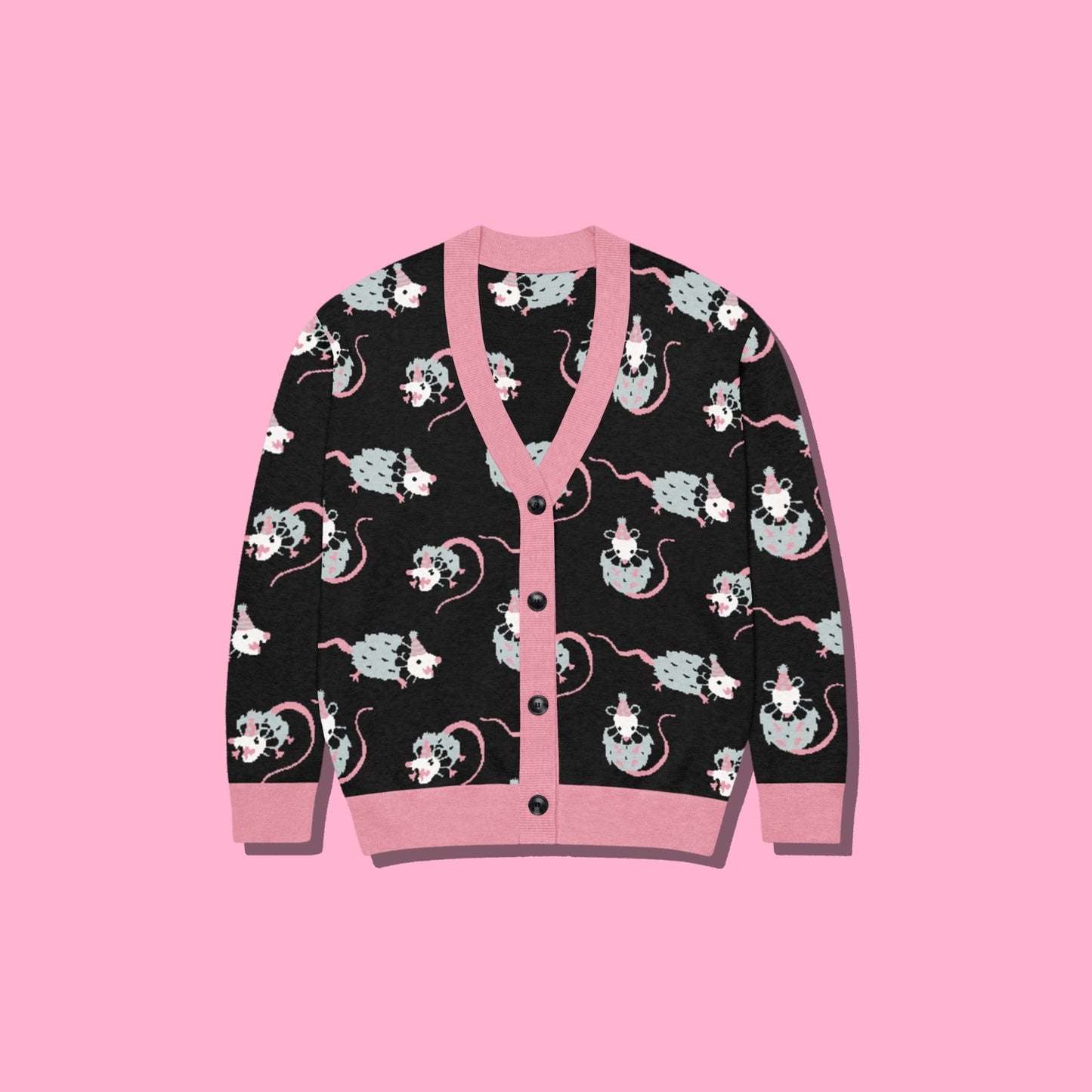 A black cardigan sweater featuring a playful pattern of cartoon clown opossums and pink trim, displayed flat against a solid pink background.