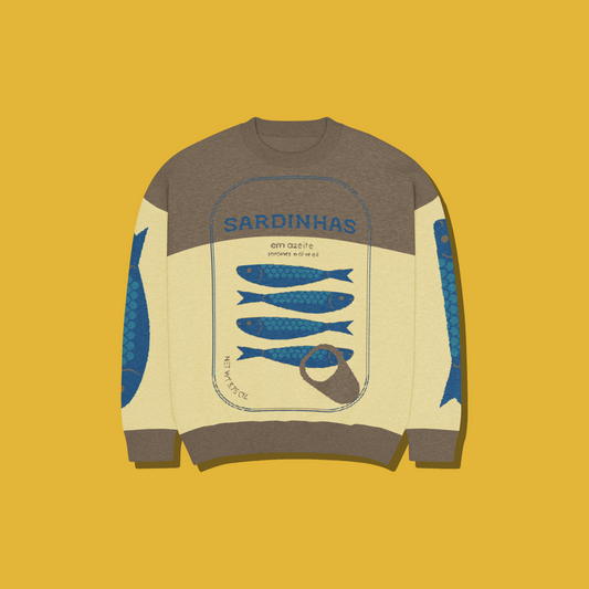 A long-sleeve crewneck sweatshirt with a color-blocked design in brown, cream, and blue, featuring a graphic of sardines and a can opener on the front, set against a solid mustard yellow background.