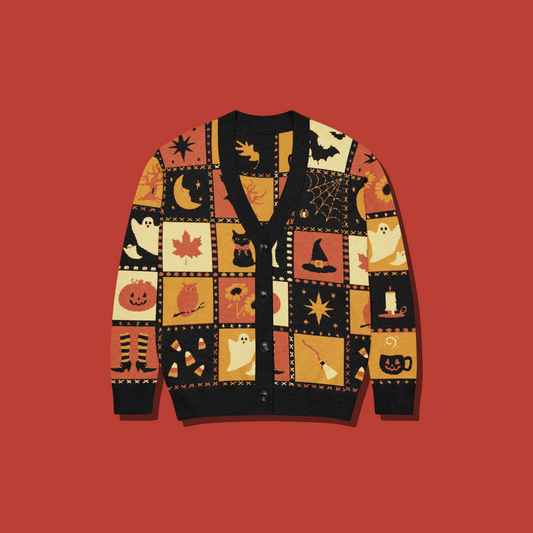 A black knit cardigan sweater with a patchwork of autumn and Halloween-themed squares, including ghosts, pumpkins, moons, stars, and brooms, shown against a solid red background.